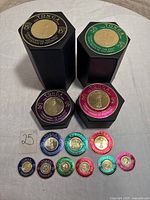 Overall view of the 13-piece Tonga 1962 gold coin commemorative stamp set on a surface showing multiple hexagonal black cases with colorful stamp fronts and smaller loose stamps.