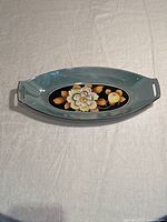 Top view of oblong celery dish showing pale blue border and central floral design on black background
