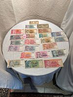 Wide view of 29 Yugoslavian banknotes spread on round table, different denominations and colors shown