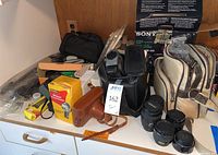 Overview of cameras, bags and lenses on a table.