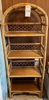 Full front view of bamboo shelving unit showing five wooden shelves and woven bamboo side panels with arched top.