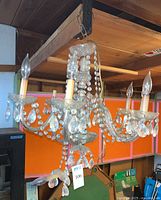 Full view of the five-armed glass chandelier with hanging crystal beads and candle-style bulbs.
