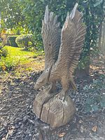 Side angle view showing the eagle sculpture with wings raised and wood texture with cracks and splits.