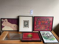 Overview shot of all five framed art pieces arranged on and above a wooden surface against a wall showing the size, framing, and general style of the artworks.