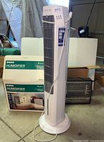 Arctic Air tower fan standing upright alongside boxed Kenmore humidifier and black Arvin electric heater behind.