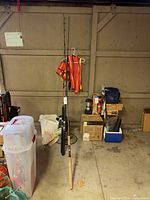Fishing poles leaning against garage door with orange safety vest hanging beside them