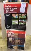 Two unopened boxes of Intermatic Malibu low voltage tier light sets with product information and instructions visible on packaging.
