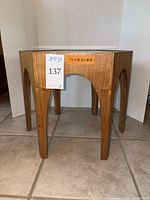 Side view of hexagonal brutalist style wooden side table with glass top.