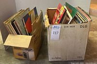Two large boxes filled with assorted vintage record albums, showing colorful album cover edges and spines with various designs.