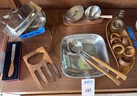 Photo showing assorted serving utensils and pieces including polished pewter, wood utensils, butter dishes, and a nut grinder.