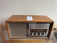 Side front view of the vintage Emerson radio on a wooden surface with power cord visible.