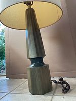 Side view of the vintage lamp showing the shape and color of the wood base and partial view of the lampshade.
