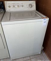 Front view of almond color Kenmore 90 Series washing machine showing control panel and appliance body.