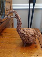 Side view of vintage Cree handcrafted tamarack twig goose decoy showing curved neck and twig body on wooden surface.