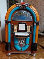 Front view of Crosley iJuke iPod jukebox player showing colorful glowing tubes and chrome accents.