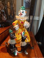 Front view of the vintage HB Japan ceramic clown with the two seal figurines on a wooden surface.