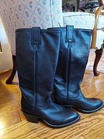 Side view of new black leather women's riding boots showing heel, toe, and pull tabs.