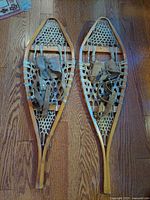 Top view of both handcrafted snowshoes showing wood frame, sinew webbing and leather bindings.