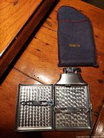 Ronson lighter opened showing textured metal interior and compartments, next to felted pouch with Ronson logo