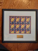 Framed sheet of commemorative stamps on wood surface