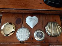 Top view of all five closed vintage compacts on wooden surface.