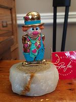 Full view of the colorful clown figurine mounted on a quartz base with gold accents and hearts.