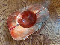 Side angle view of vintage hand crafted orange jasper trinket dish showing natural grain and polished central bowl.