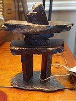 Front view of the handcrafted stone Inuksuk showing the base, vertical pillars, horizontal slab, middle rounded stone and top triangular stone arrangement.