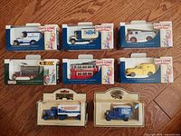 Group of nine boxed vintage Lledo Days Gone By diecast model vehicles displayed together on wooden floor.