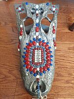 Top view of handcrafted gator folk art sculpture showing detailed beadwork in red, white, and blue beads on a textured silver metallic surface.