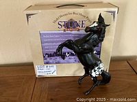 Black Breyer horse model in rearing pose with white spotted hindquarters and red eyes and nostrils displayed in front of original box.