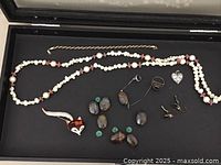 Overview of the costume jewelry lot including a fox pin, necklace, rings, loose stones, small heart charm, bracelet, and earrings.