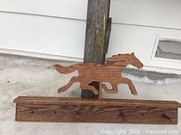 Wood rack with running horse cutout on wood plank with mounting holes for hanging