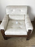 Front view of white Naugahyde upholstered mid-century modern side chair with wood frame showing tufted backrest and seat.