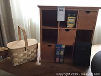 Wooden cubby unit with some wooden bins, woven basket, and an office supply box on a wooden table