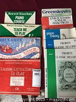 Photo showing a variety of children's piano sheet music and instructional books with colorful covers and readable titles.