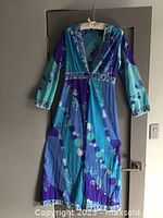 Full length of the vibrant blue and purple loungewear dress with geometric and circular patterns hung on door.
