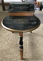 Front view of the vintage telephone table showing hand-painted floral design on round wooden top with attached slanted compartment.