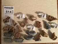 Photo showing multiple Wade ceramic animal figurines including white polar bears, brown birds, and blue aquatic animals arranged on a beige surface.