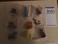 Nine porcelain Wade Red Rose Tea collecting figurines arranged on a paper background, each individually bagged and showing various animals and shapes in multiple colors