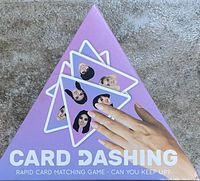 Purple triangular box of Card Dashing rapid card matching game with cards illustrated with facial portraits.