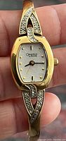 Close-up of a gold tone Caravelle by Bulova women's wristwatch with rhinestone accents on the band and an oval dial.