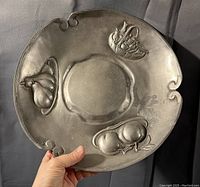 View of embossed tin plate showing fruit decorations and scalloped edges