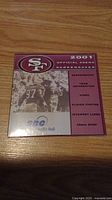 Front side of the 2001 official 49ers screensaver CD-ROM package showing logo, team image, and content summary.