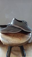Pair of Aldo men's gray perforated leather lace-up casual shoes, side view, placed on wooden stool.
