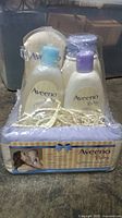 Front view of Aveeno Baby bath care package with four bottles in a decorative box with shredded paper filler, showing brand and packaging details.