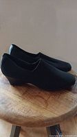 Side view showing the profile and wedge heel of the black women's shoes.