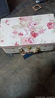Closed floral decorative box with pink rose print and metal latch handle.