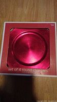 Photo of the set of 4 round red chargers in original packaging.