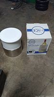 Photo of the small round bar ice cooler with white lid and stainless steel base, next to its original box labeled 'Nice Ice Cooler'.